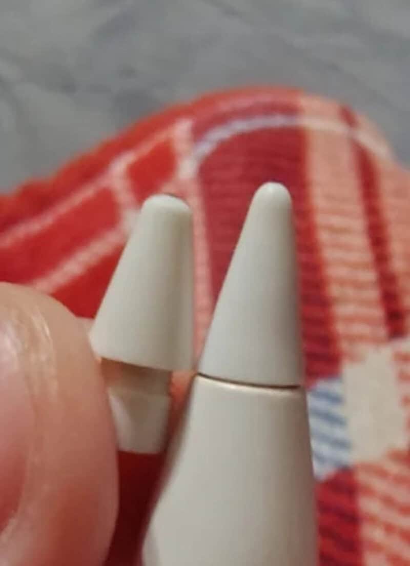 Close-up of two white cone-shaped objects held by fingers, with a red and white striped fabric in a.