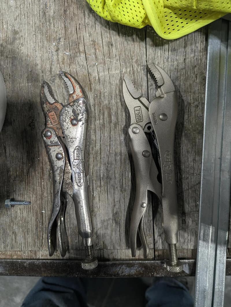 Two adjustable pliers on a wooden workbench, one smaller and one larger.