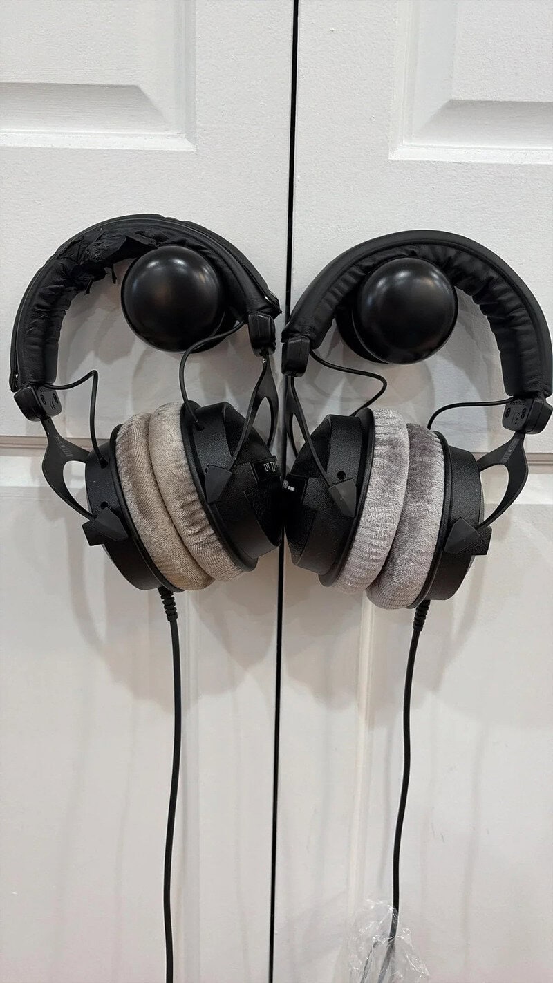 Pair of black and beige over-ear headphones hanging on a white door.