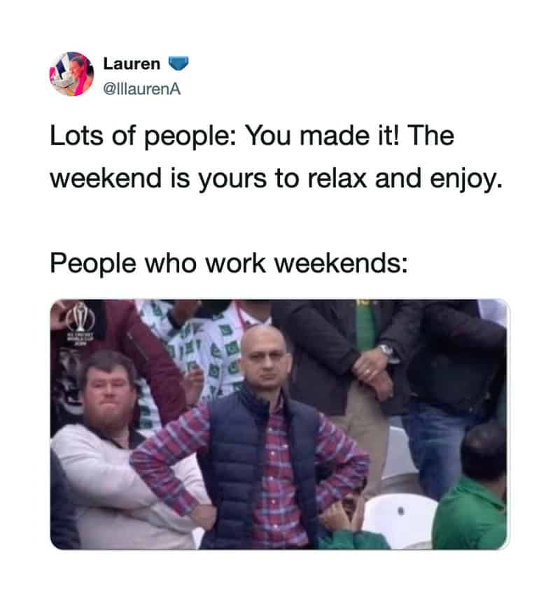 People at a sports event, some standing and some sitting, with a man in a plaid shirt and vest in in.