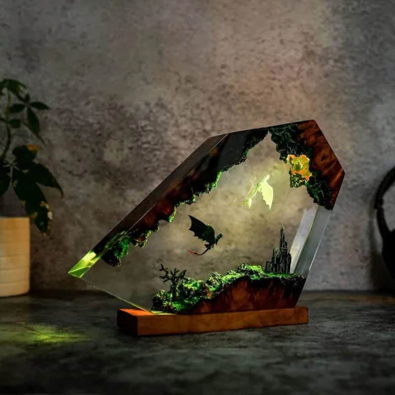 Decorative glass art with a fantasy landscape scene, including a castle and flying dragon.