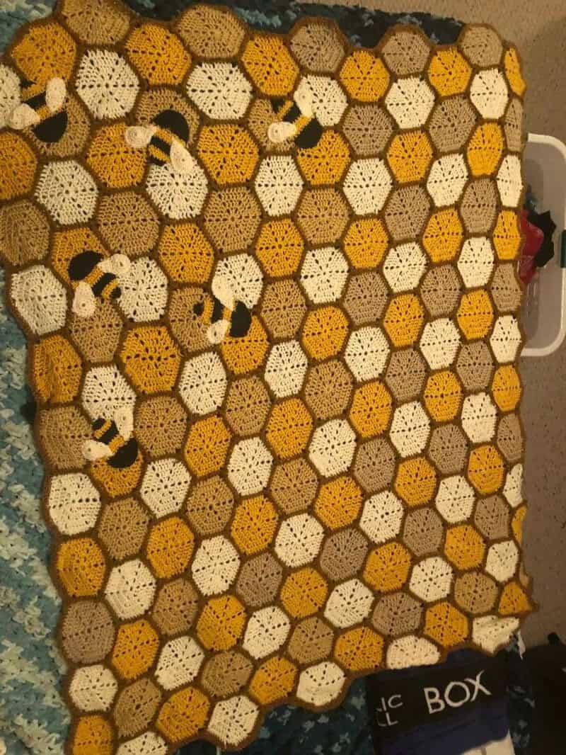 Crocheted blanket with honeycomb pattern and bee appliqués.