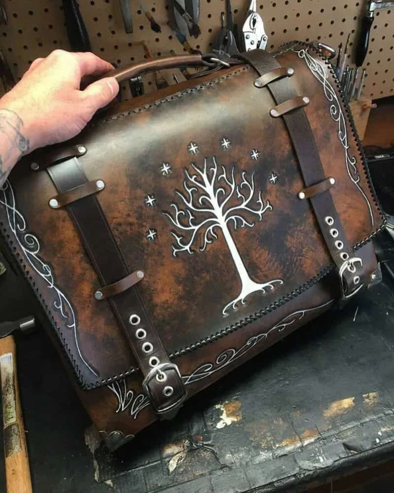 Leather bag with a white tree and star design, metal buckles, and decorative patterns.