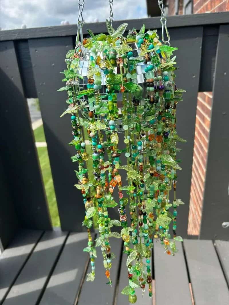Colorful hanging wind chime made of green, blue, and orange beads and glass pieces.