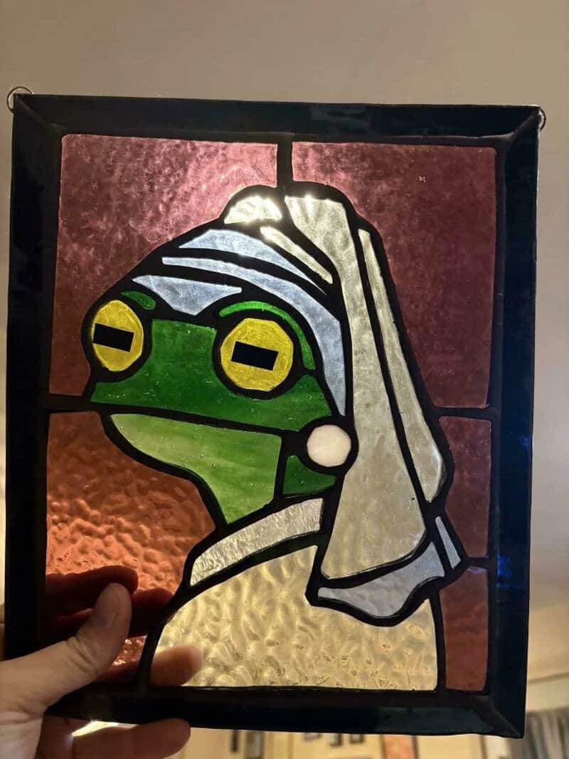 Stained glass art of a frog wearing a nurse's cap, with a pink background.