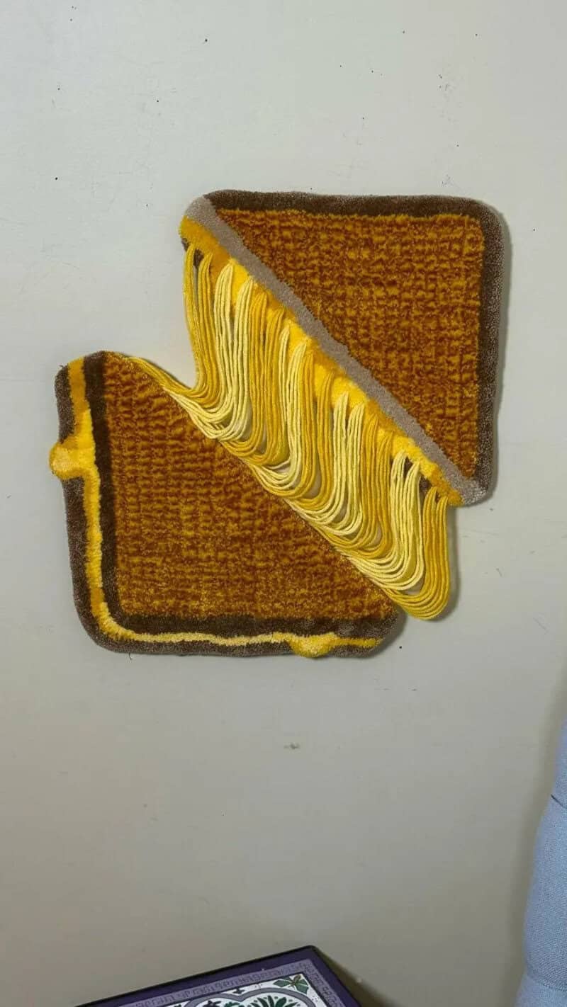 A brown and yellow woven rug with fringes, folded in half, on a white surface.