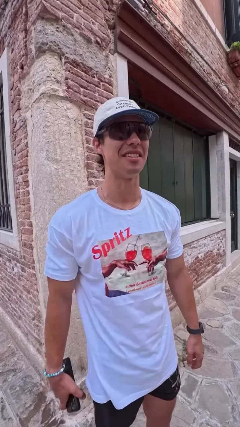 Young man in sunglasses and a cap standing on a Venetian street.
