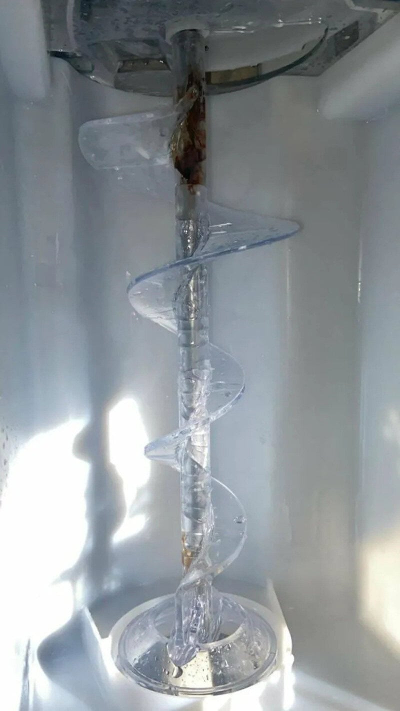 Ice spiral inside a freezer with rust and water damage.