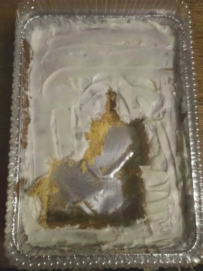 Empty aluminum tray with leftover cake and white frosting.