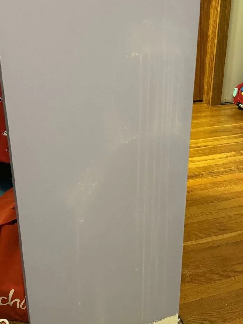 White door with scratches and a wooden floor in the background.
