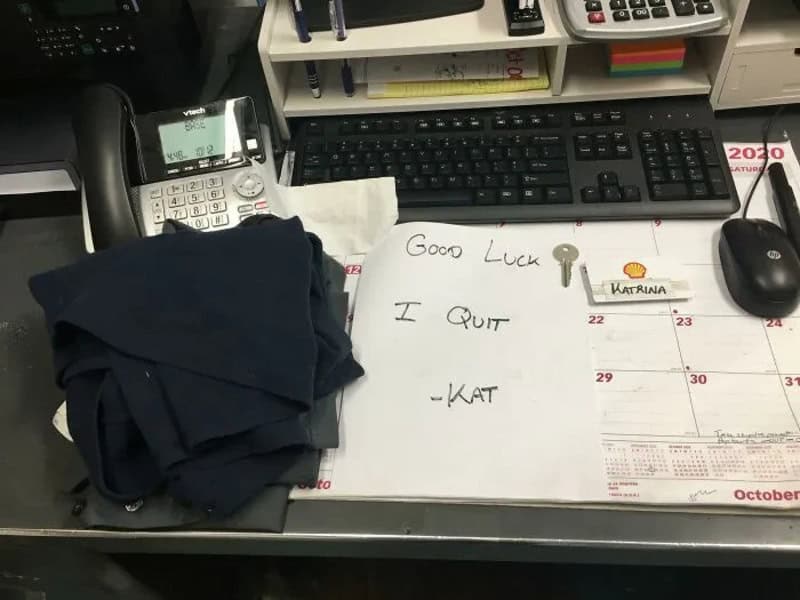 Desk with a phone, keyboard, mouse, and a note saying 'Good Luck I Quit - KAT'.