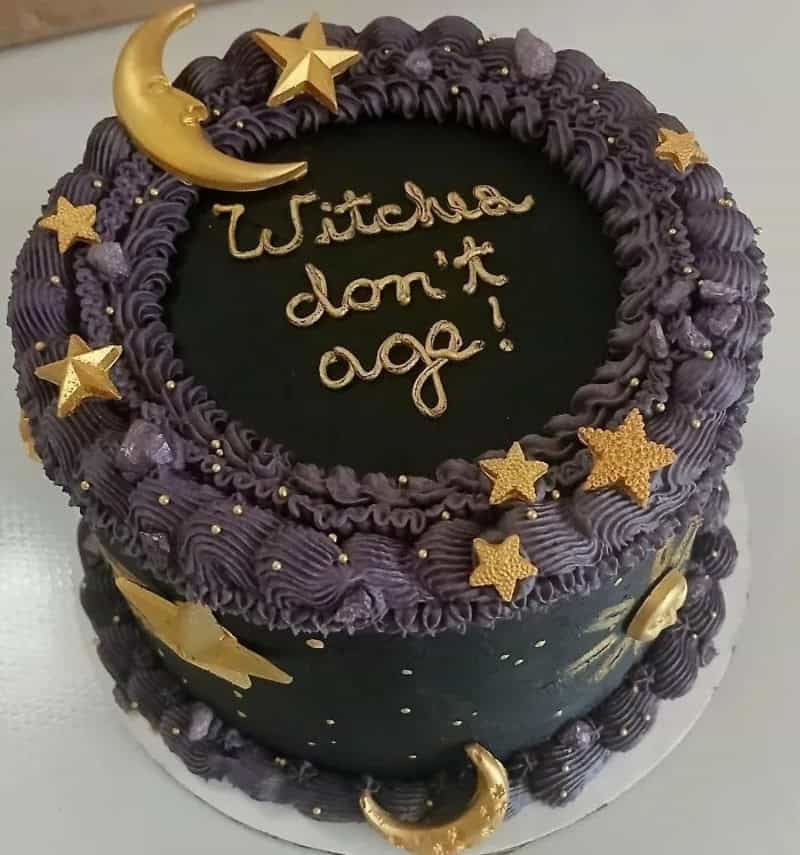 Decorative cake with purple frosting, gold stars, moons, and 'Witcha don't age!' written on top.