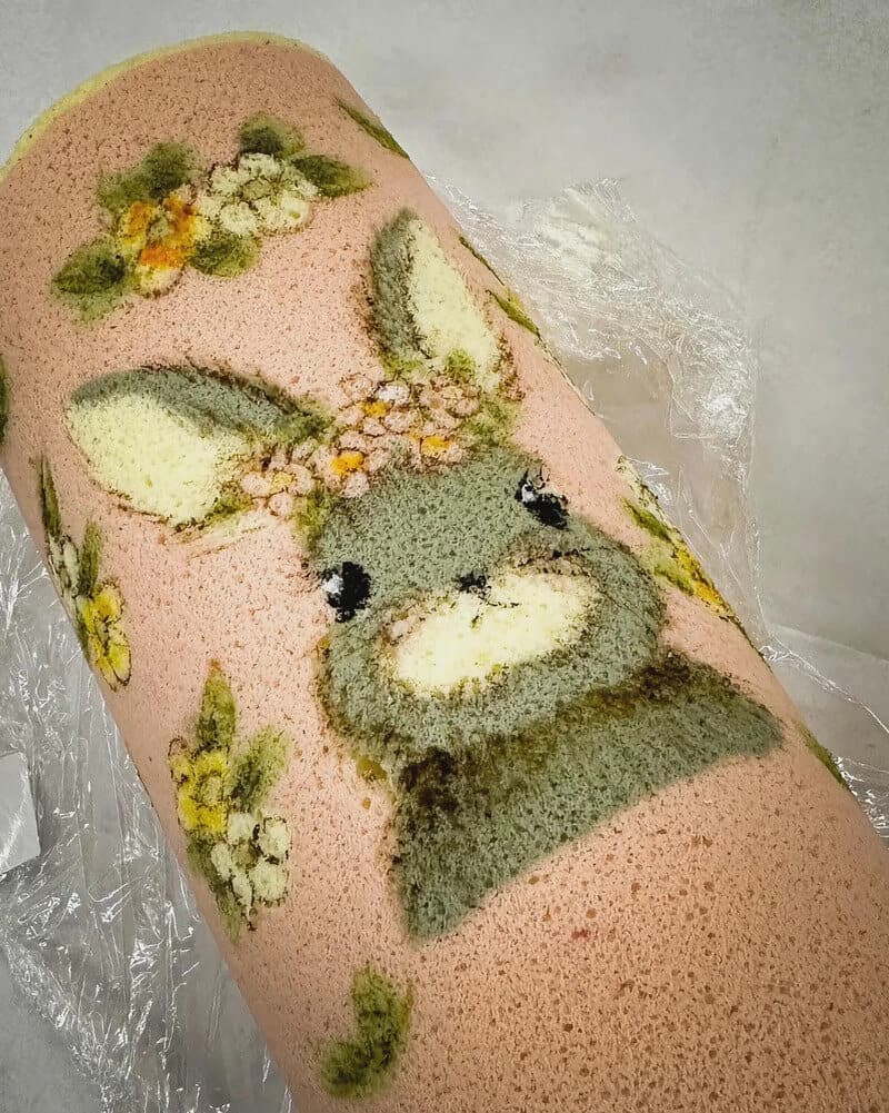 Pink cake with a bunny and floral design, wrapped in clear plastic.