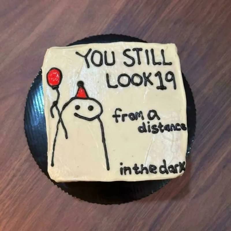 Cake with a drawing of a smiling face, party hat, and balloon, with text about COVID-19.