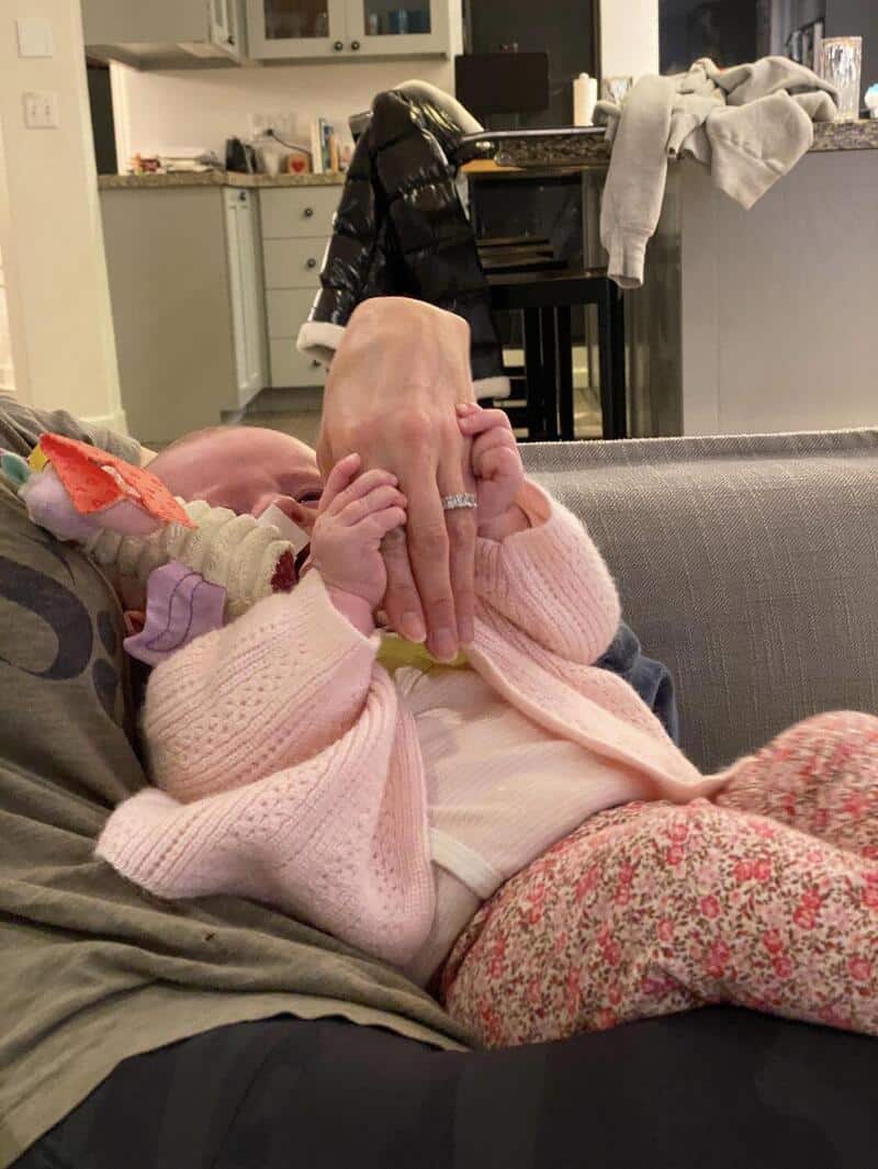 Child holding an adult's hand in a cozy living room.