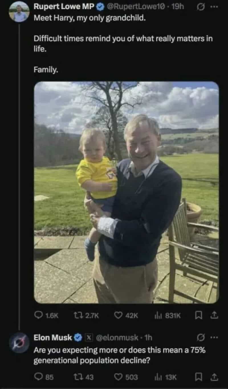 A man holding a young child outdoors on a sunny day with trees and a field in the background.