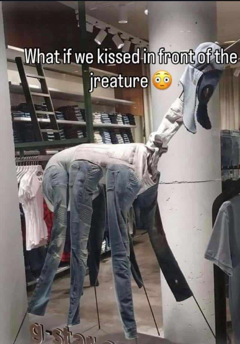 Humorous sculpture of a creature with jeans and a shirt, with the caption about kissing in front of.