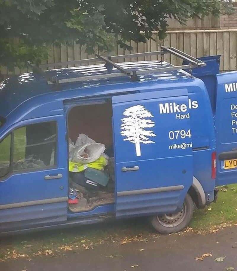 Blue work van with open sliding door, showing tools and equipment inside.