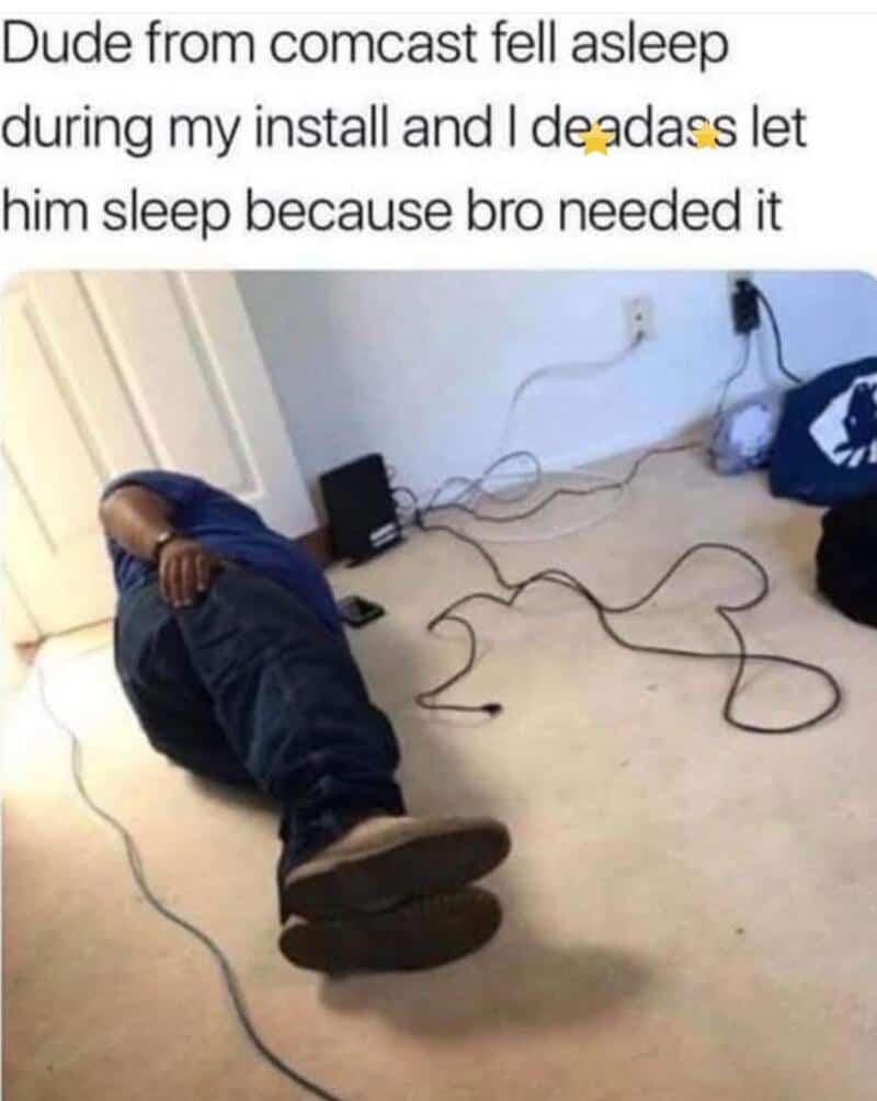 Person sleeping on the floor with tangled cables around him, a power strip and a bag nearby.
