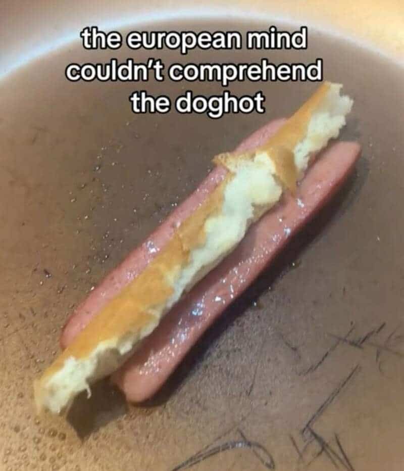 The image shows a hot dog with a piece of bread on top, in a frying pan.