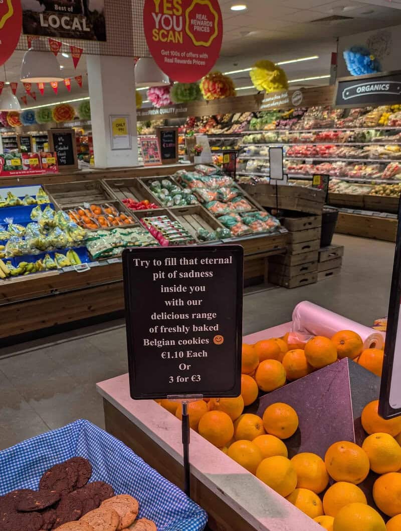 Sign in a grocery store promoting Belgian cookies and oranges.