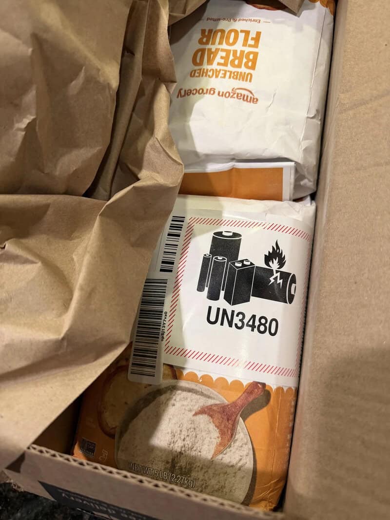 Box of batteries with UN3480 warning label and a spoon with salt.