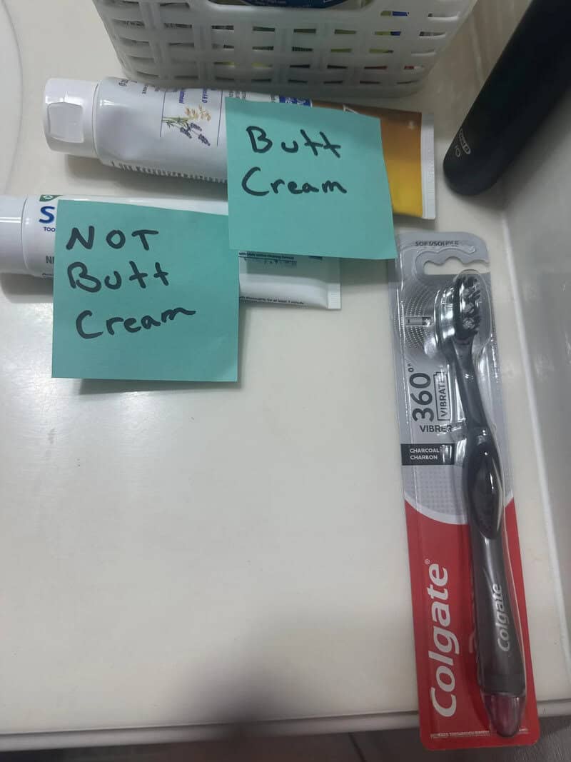 Toothpaste and toothbrush with sticky notes labeled 'Butt Cream' and 'NOT Butt Cream'.