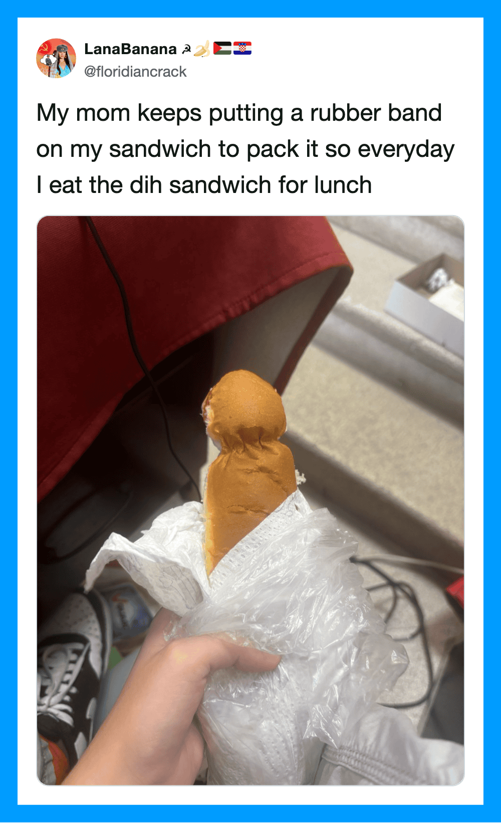 Person holding a hot dog with a rubber band on top, in a plastic bag.