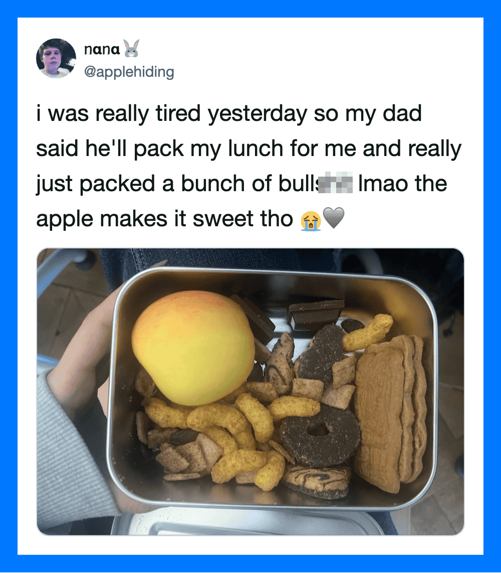 A lunchbox with an apple, snacks, and chocolate bars, shared in a tweet about a dad packing lunch.