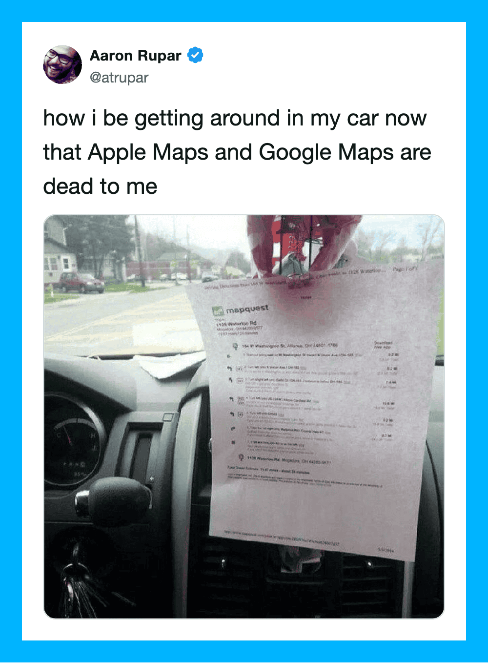 Car dashboard with a paper hanging from the rearview mirror, showing a receipt or document.