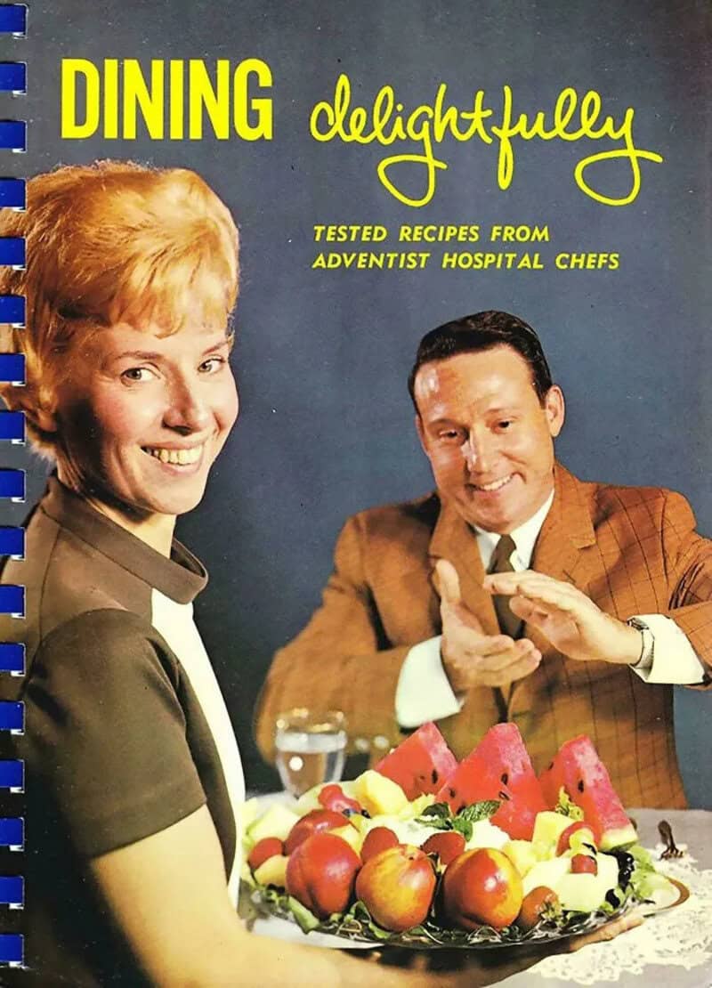 Book cover titled 'Dining delightfully' with a woman and man smiling at a table with fruit.