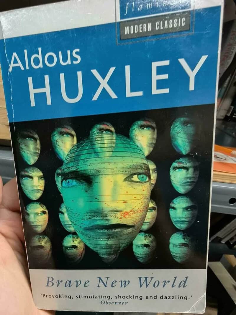 Book cover of 'Brave New World' by Aldous Huxley, featuring a large face with multiple smaller faces.