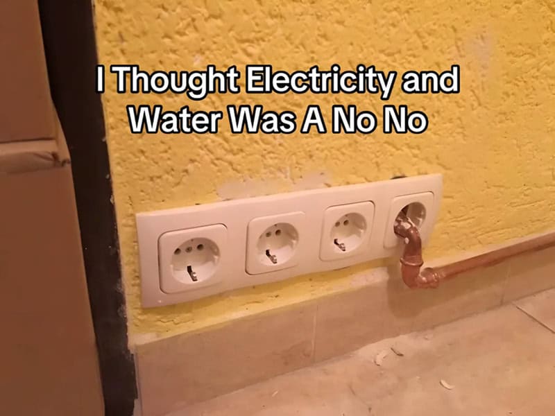 Four electrical outlets with a pipe connected to one, above a yellow wall.