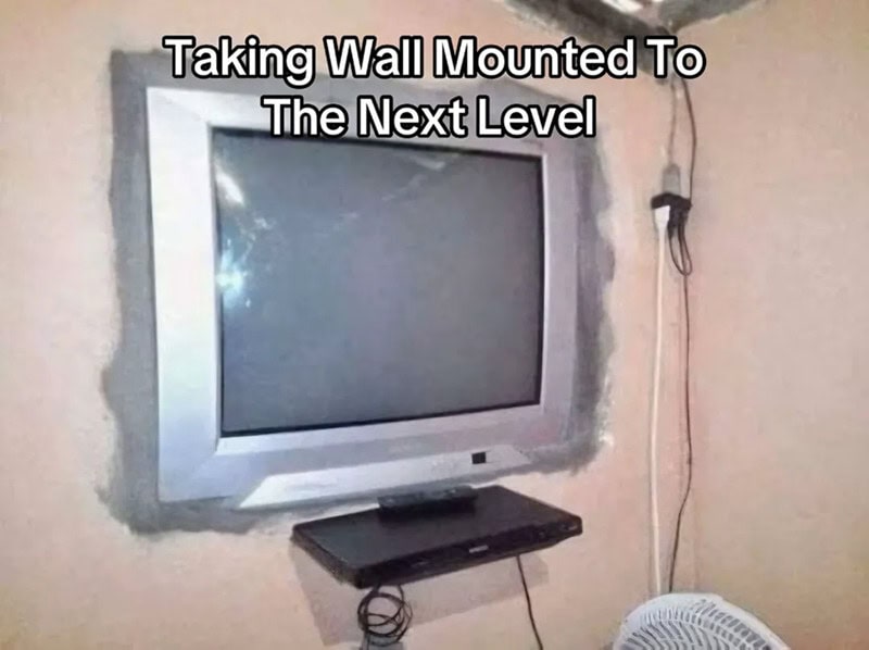 Wall-mounted TV with a shelf below, captioned 'Taking Wall Mounted To The Next Level'.