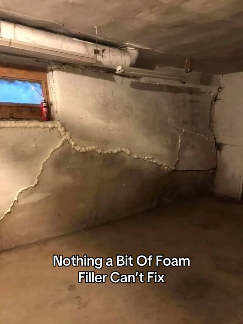 Cracked basement wall with foam filler attempt and small window.