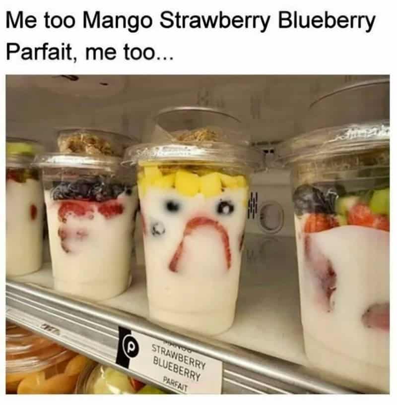 Yogurt cups with fruit arranged to look like faces, with a sad face in the middle.