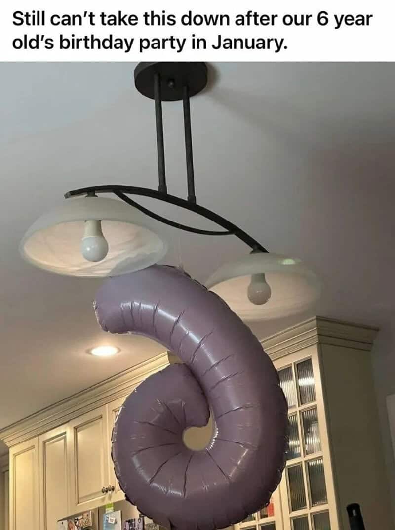 Light fixture with a purple balloon twisted into a spiral shape.
