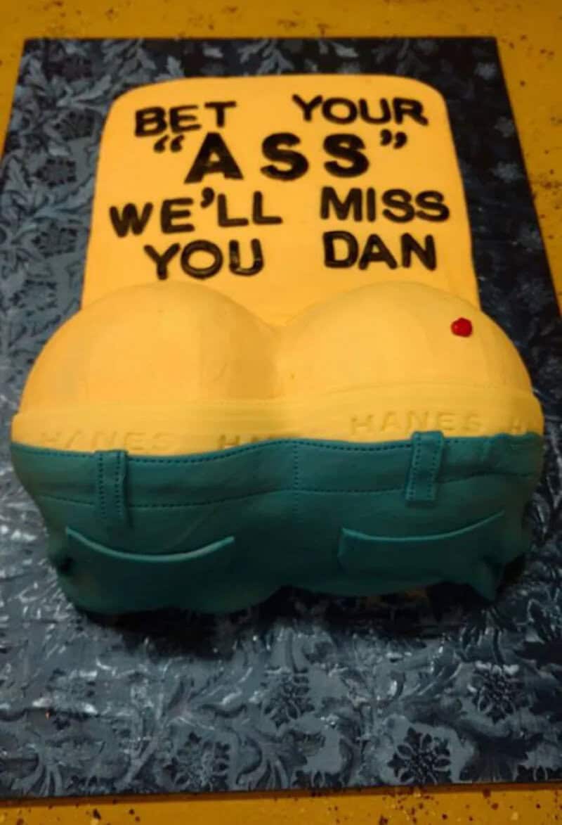 Humorous cake with a sign saying 'Bet your ass we'll miss you Dan'.
