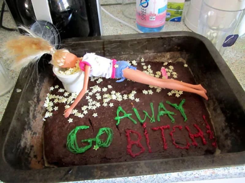 Barbie doll lying on a cake with 'GO AWAY BITCH' written on it.