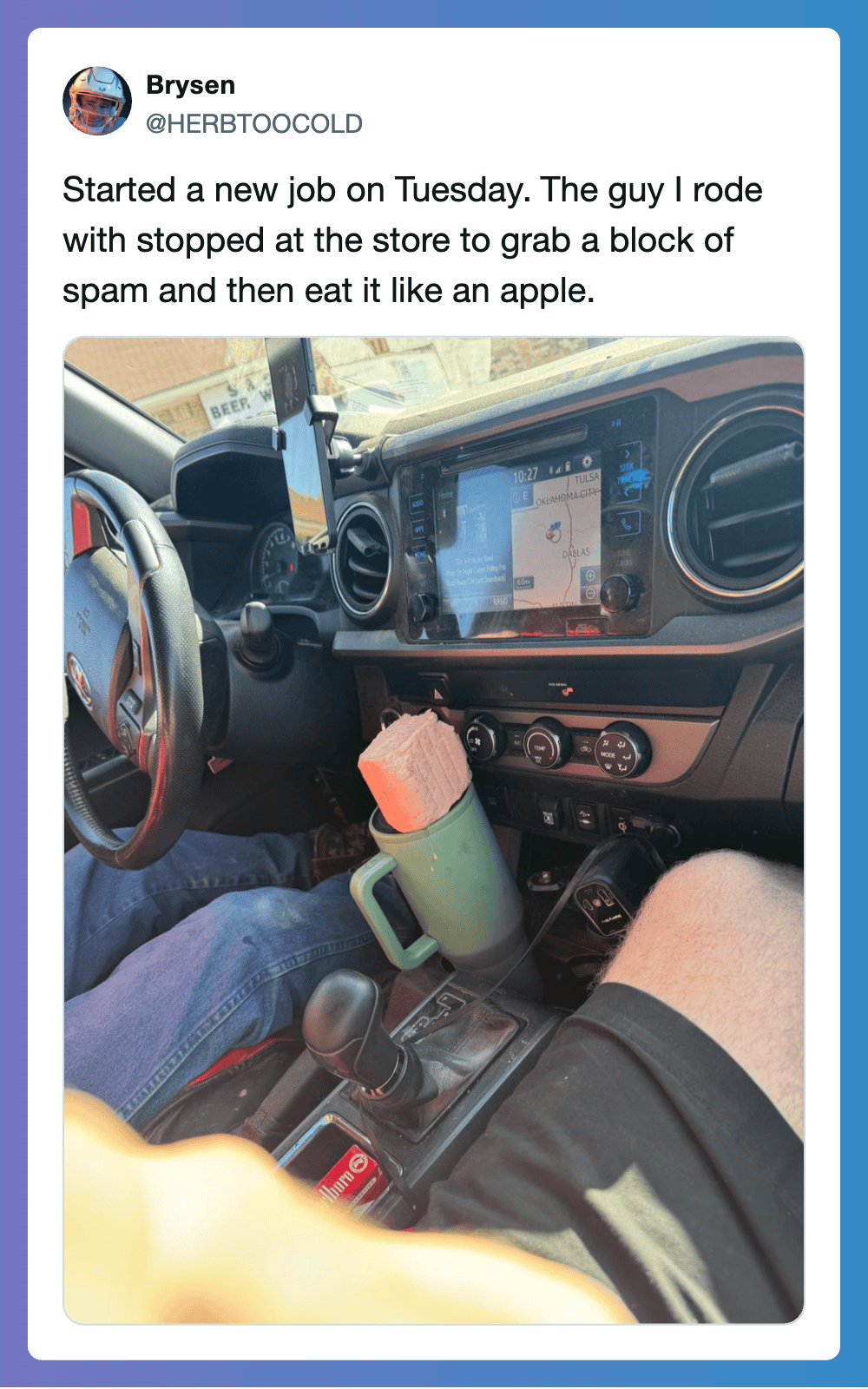 Person in a vehicle with a drink and a phone, dashboard visible, during daytime.