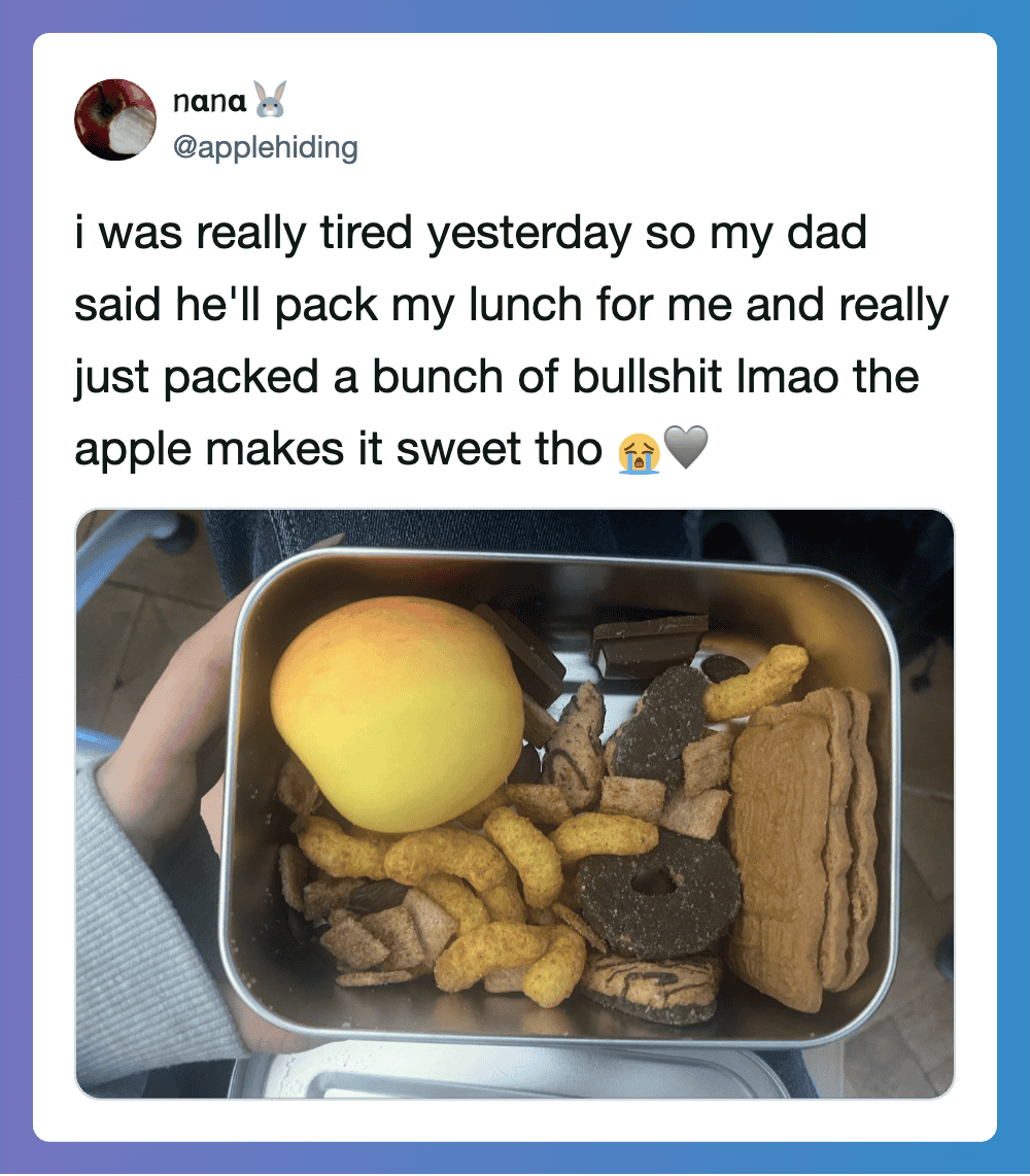 A lunchbox with an apple, chocolate, and snack bars, shared in a tweet about a dad packing lunch.