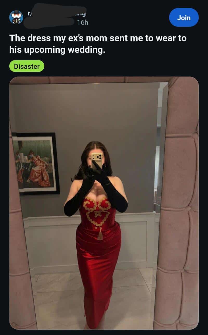 Woman in a red dress taking a mirror selfie, with a framed picture on the wall behind her.