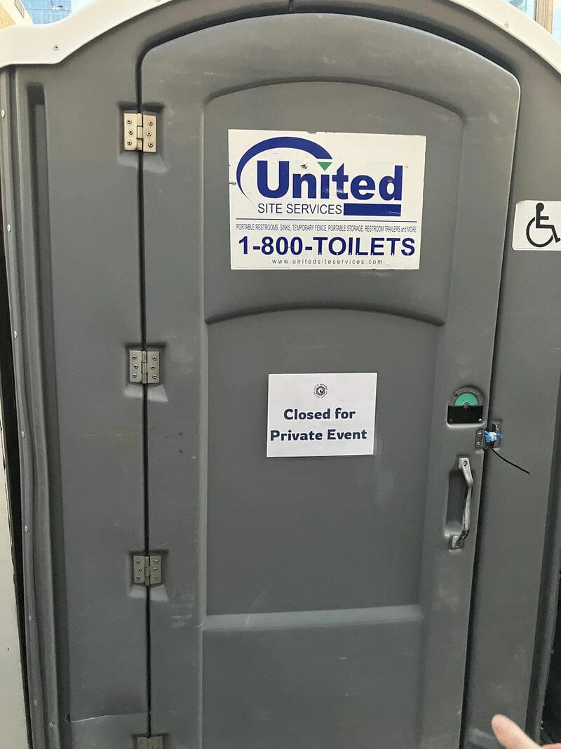 Portable toilet with United Site Services sign and 'Closed for Private Event' notice.