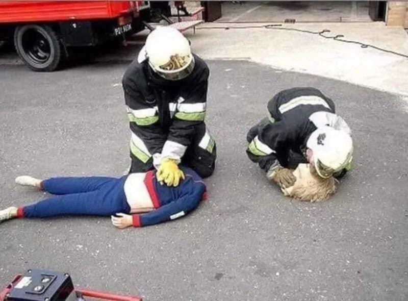 Firefighters attending to a person lying on the ground during an emergency.
