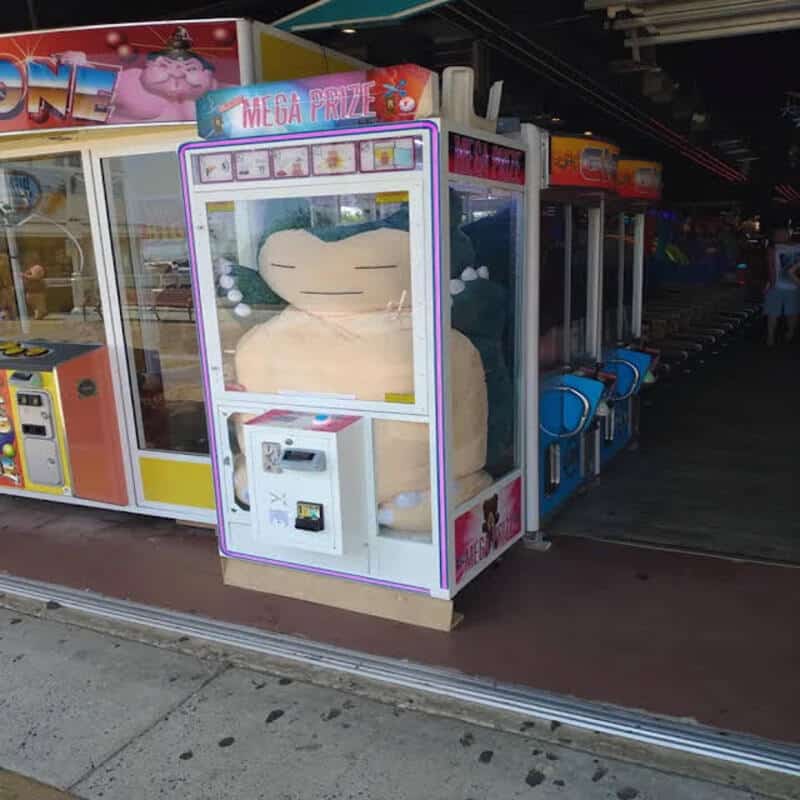 Large plush dinosaur inside a claw machine at an arcade.