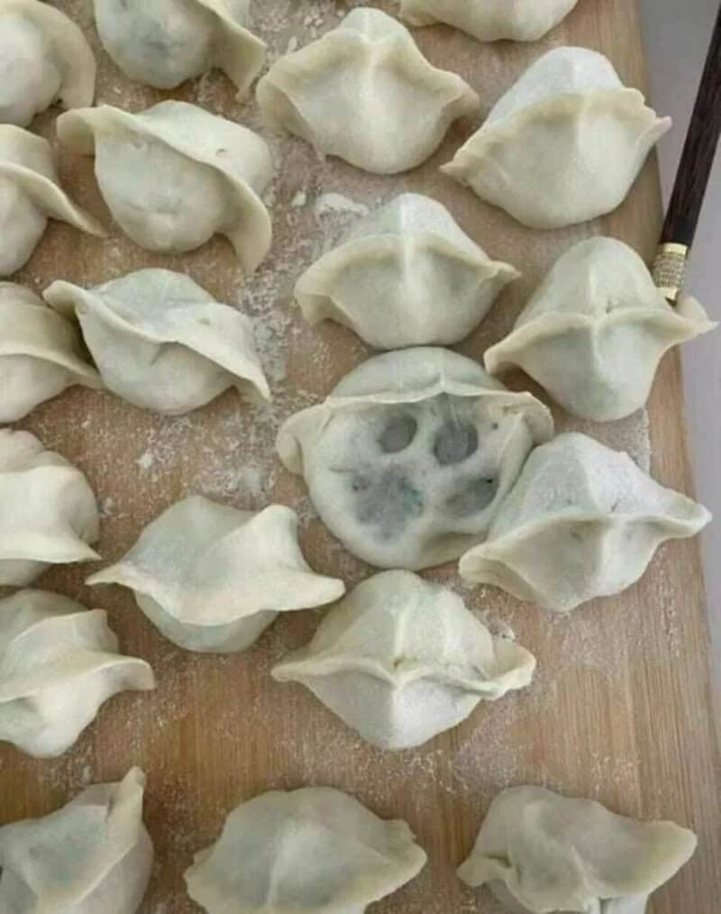 Dumplings on a wooden surface, one with mold, resembling a face.