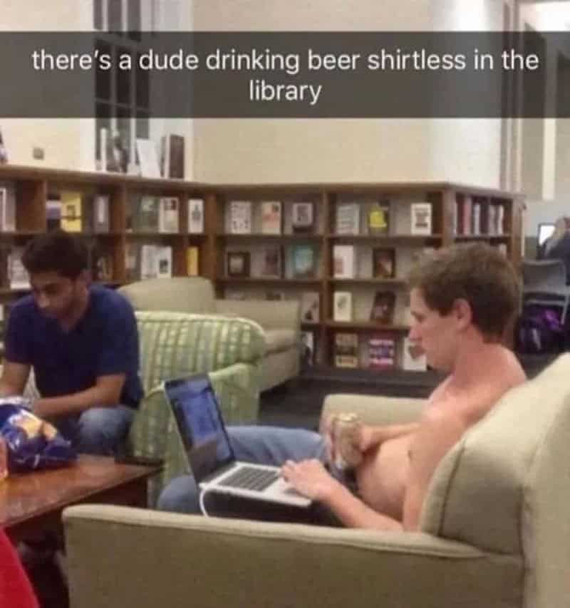 Dude drinking beer shirtless in the library with laptop and friends.