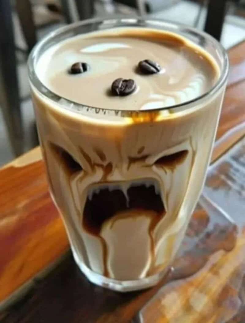 Coffee drink with a face, eyes, and mouth, on a wooden table.