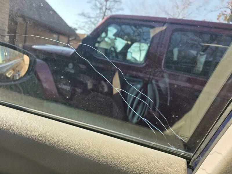 Cracked car windshield with spiderweb pattern of damage.