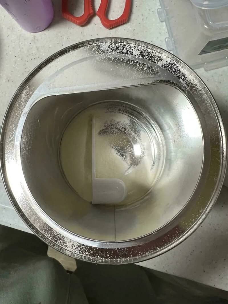 Top view of a stainless steel mixing bowl with a white spatula inside.